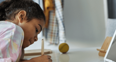 garota negra escreve com caneta numa mesa com tablet
