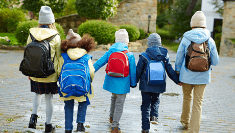 cinco crianças jovens caminham de mãos dadas agasalhadas e mochila nas costas