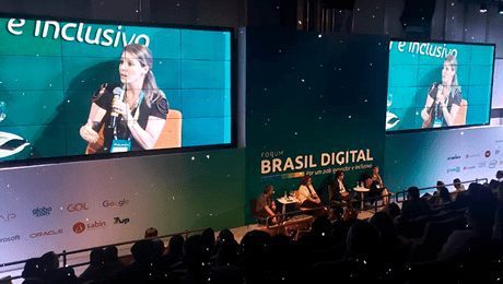 Fórum Brasil Digital vista de cima de auditório com dois telões projetando priscila cruz ao microfone