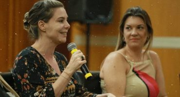 Priscila Cruz fala ao microfone enquanto é observada por mulher ao seu lado