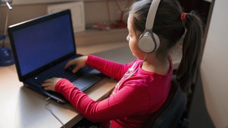menina com fones de ouvido usa computador portátil