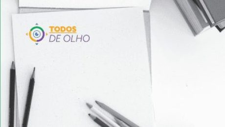 alguns lápis sobre uma folha em branco com logomarca Todos de Olho no topo