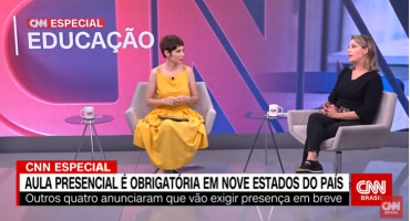 Print de tela exibição CNN Especial Educação. Duas mulheres sentadas conversando. Uma usa um vestido amarelo, tem cabelos curtos. Outra, veste calça e blusa pretas, tem cabelos louros.
