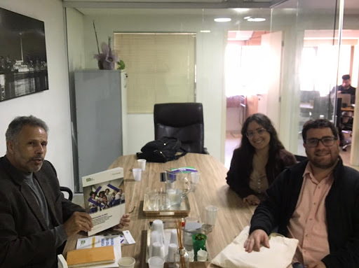 Três pessoas sentadas em uma mesa de reunião