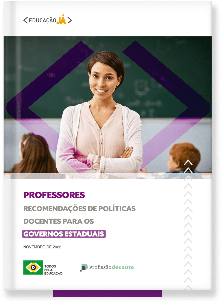 Professora de cabelos cursos e pele branca sorri de braços cruzados