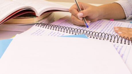 uma mão escrevendo a caneta em um caderno