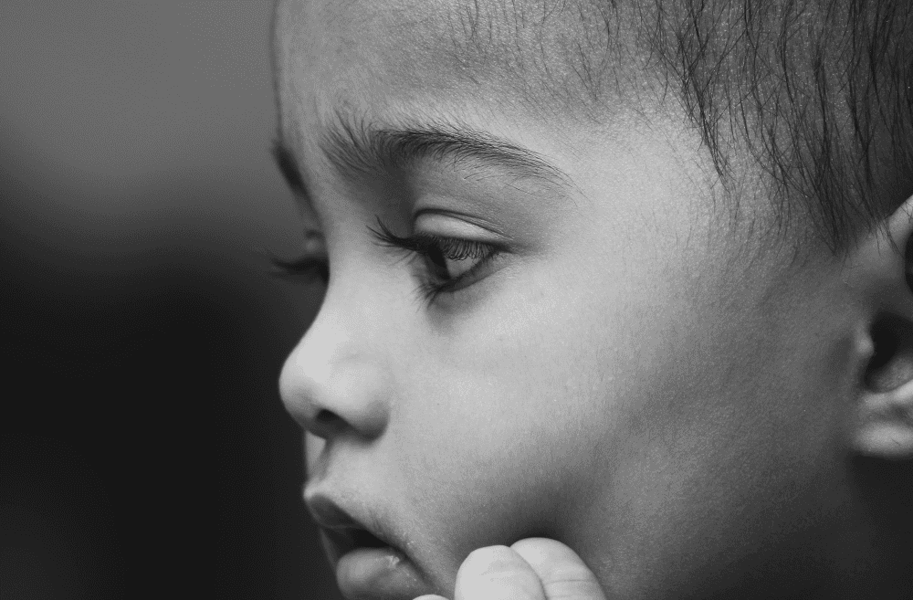rosto de criança de lado em preto e branco. Olhar reflexivo