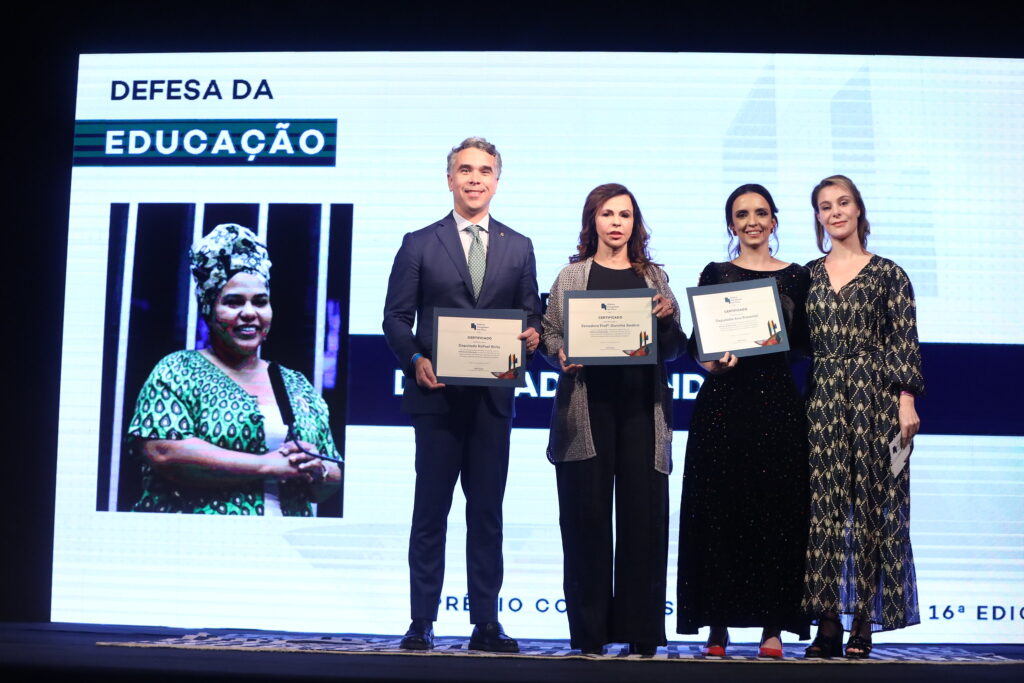 três pessoas seguram um certificado ao lado de Priscila Cruz, durante Premiação