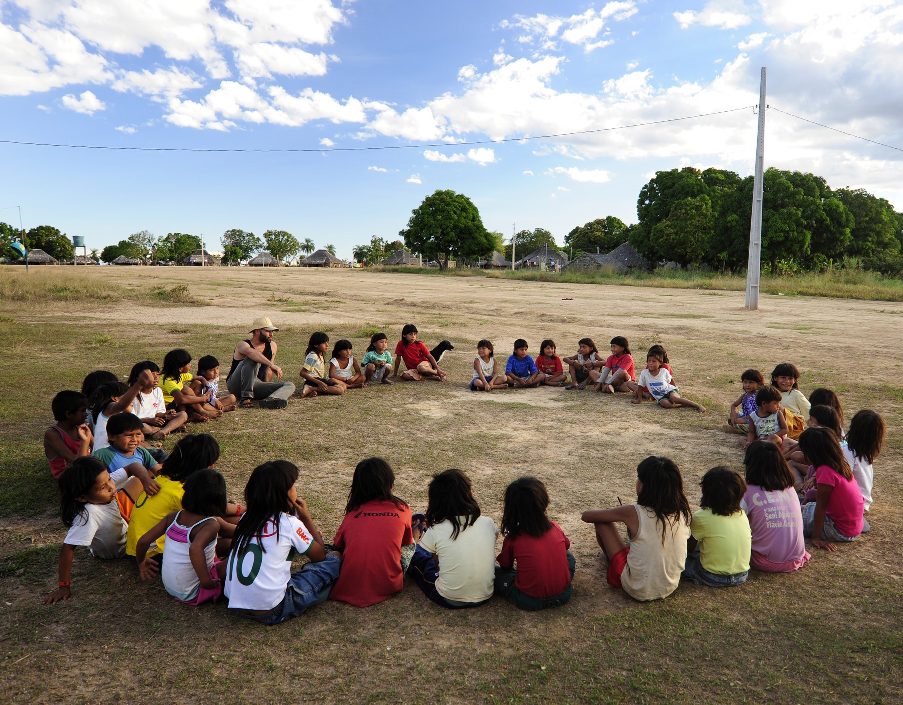 crianças indigenas sentadas no chão da aldeia