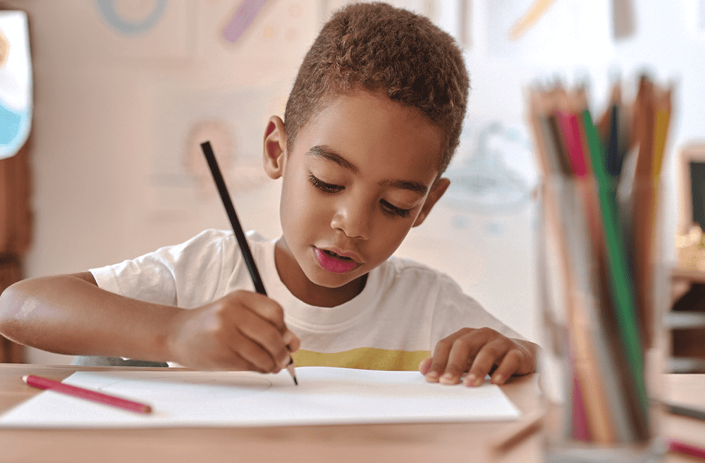 criança parda de cabelos castanhos claros e curtos escreve com lápis numa folha