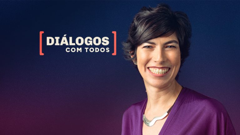 Imagem com fundo em degradê azul escuro e roxo. À esquerda, aparece o texto “[DIÁLOGOS] COM TODOS” em letras maiúsculas claras, com a palavra “DIÁLOGOS” destacada entre colchetes em vermelho. À direita, há o retrato de Gabriela Lotta, uma mulher sorridente, de cabelo curto e escuro, usando blusa roxa e um colar prateado de formato curvo. Ela está posicionada de frente, levemente inclinada para a câmera.